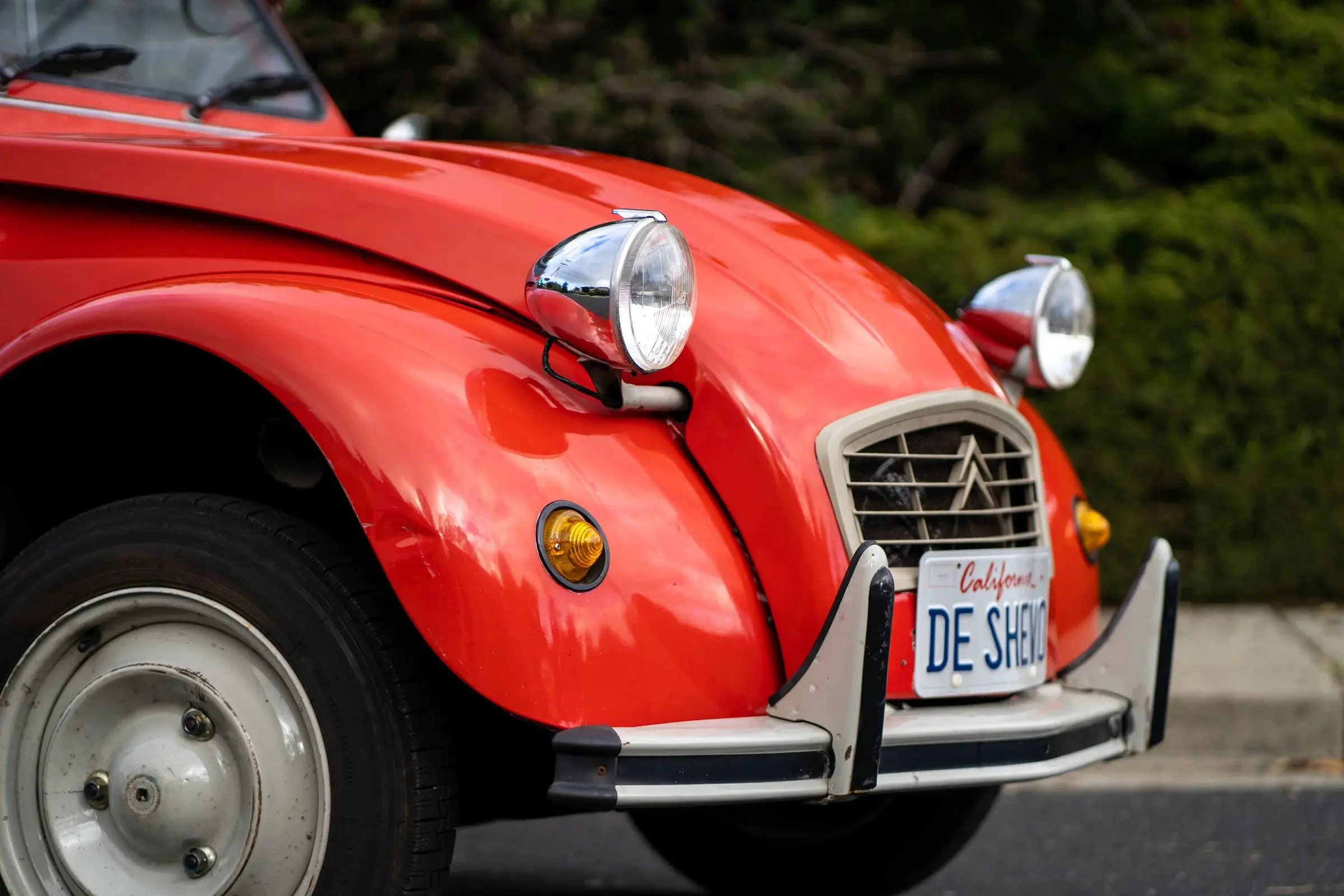 Close-up of the headlight and grille of a red Citroën 2CV