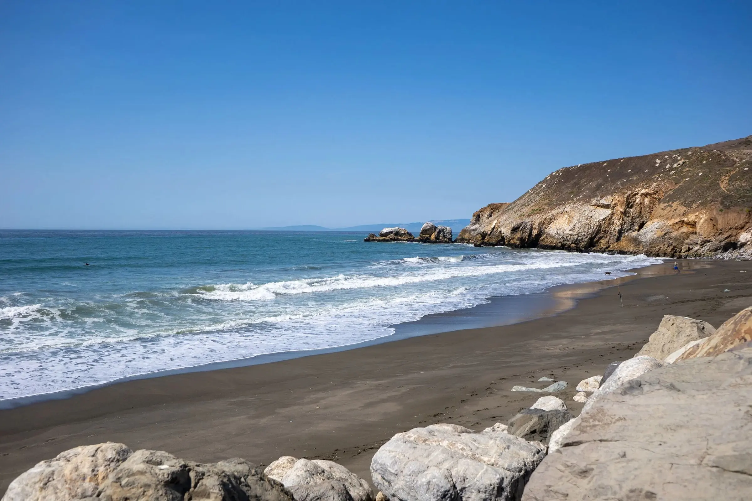 Waves rolling onto a beach under a clear sky
