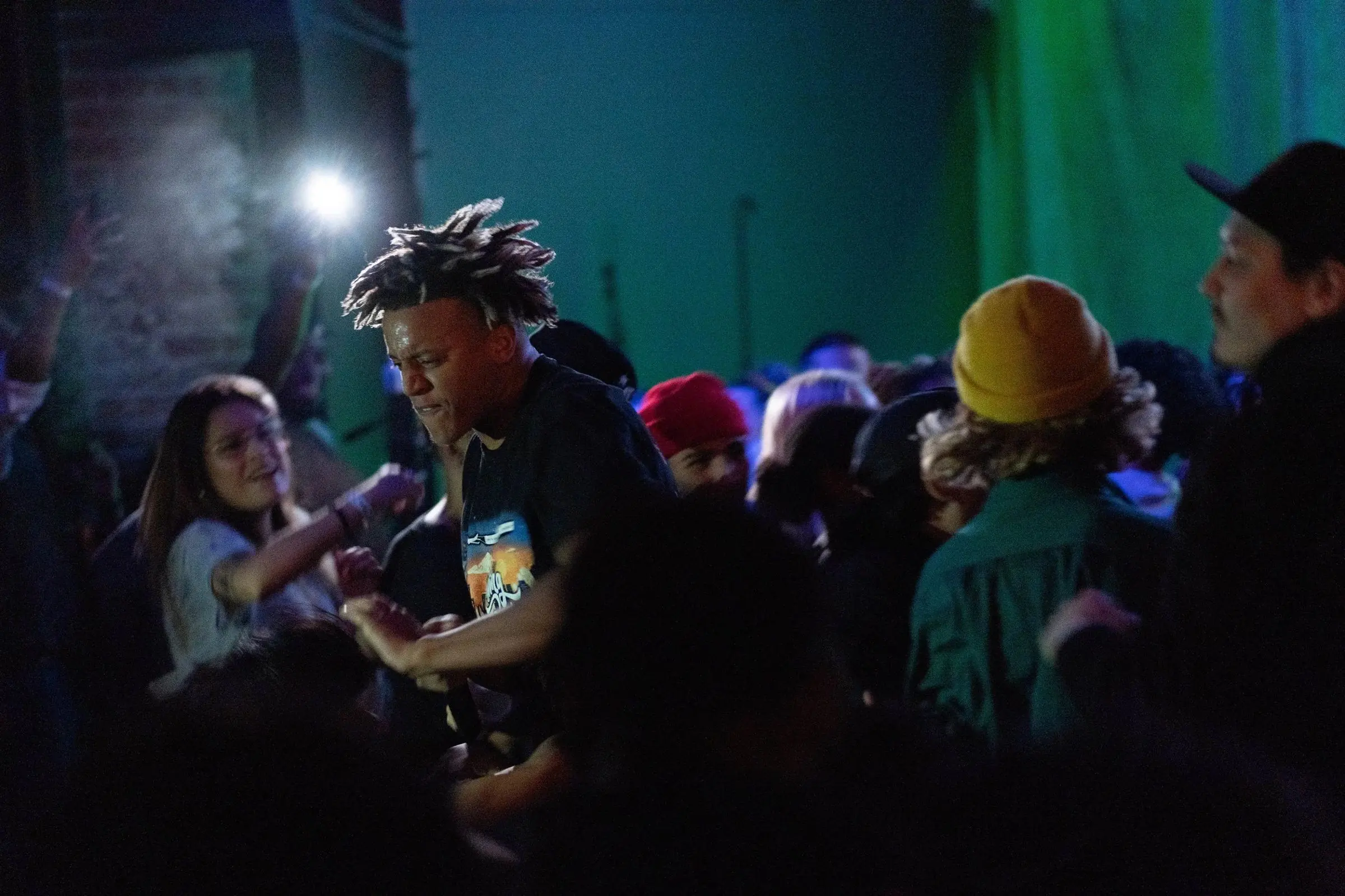 A performer mid-verse in a packed, dark club crowd