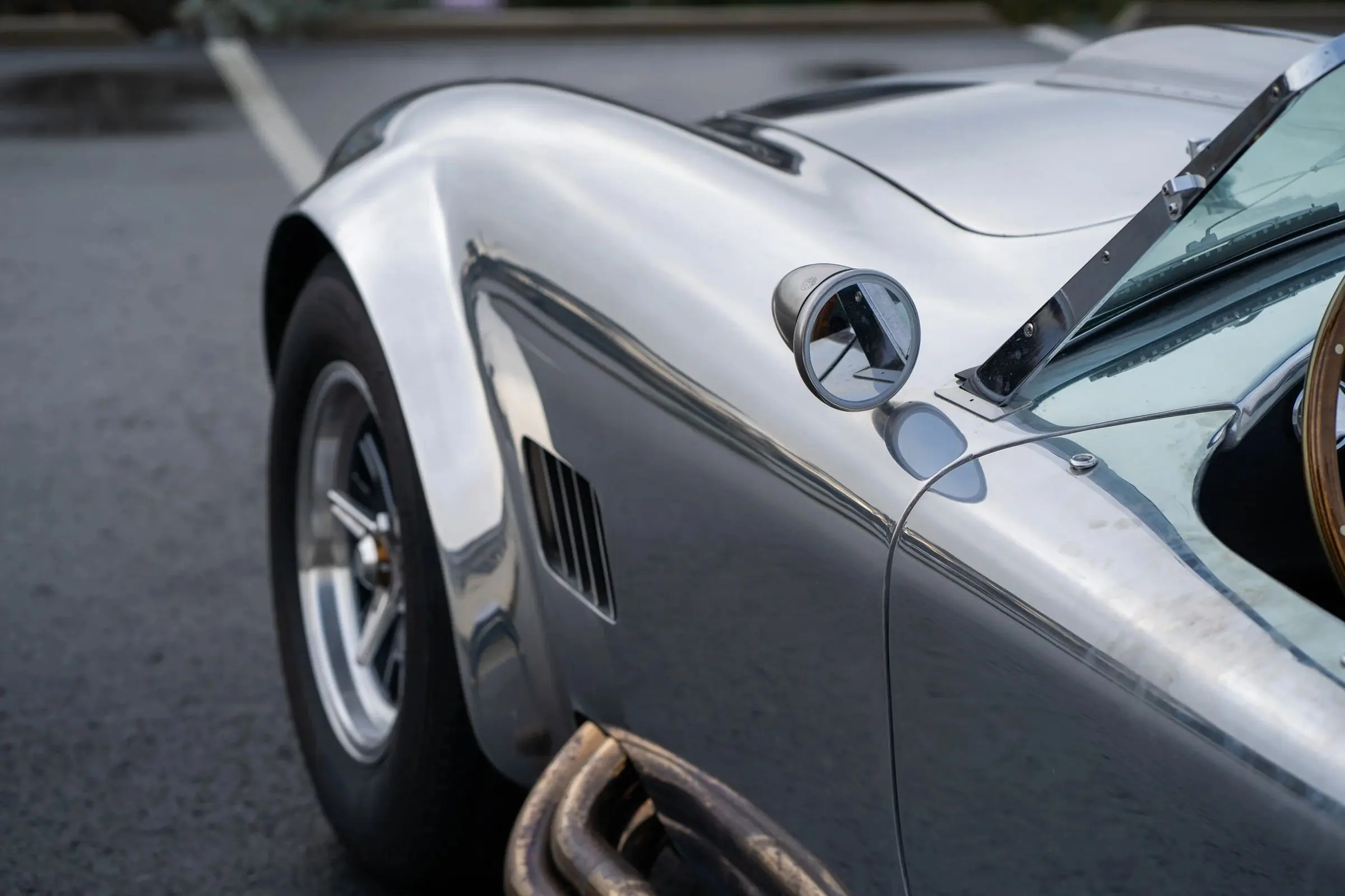 The polished aluminium flank of a classic roadster
