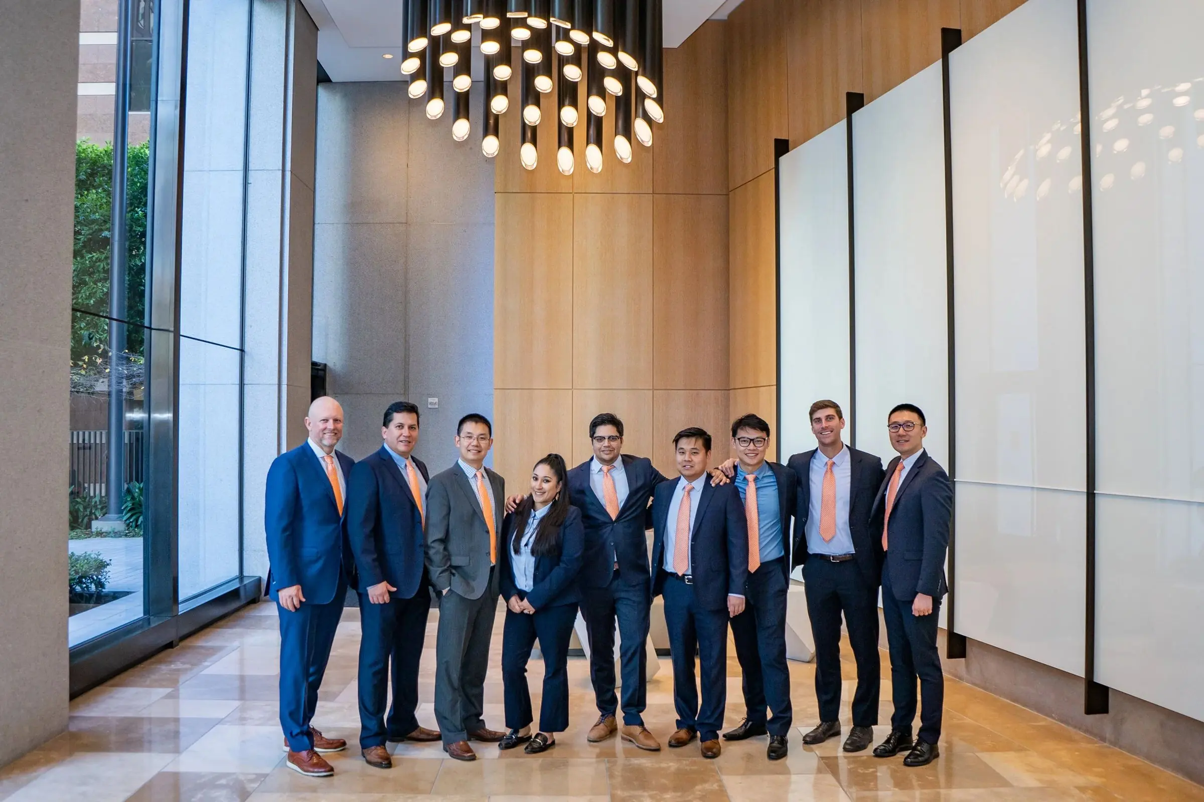 A team of ten in suits standing together in a bright modern lobby