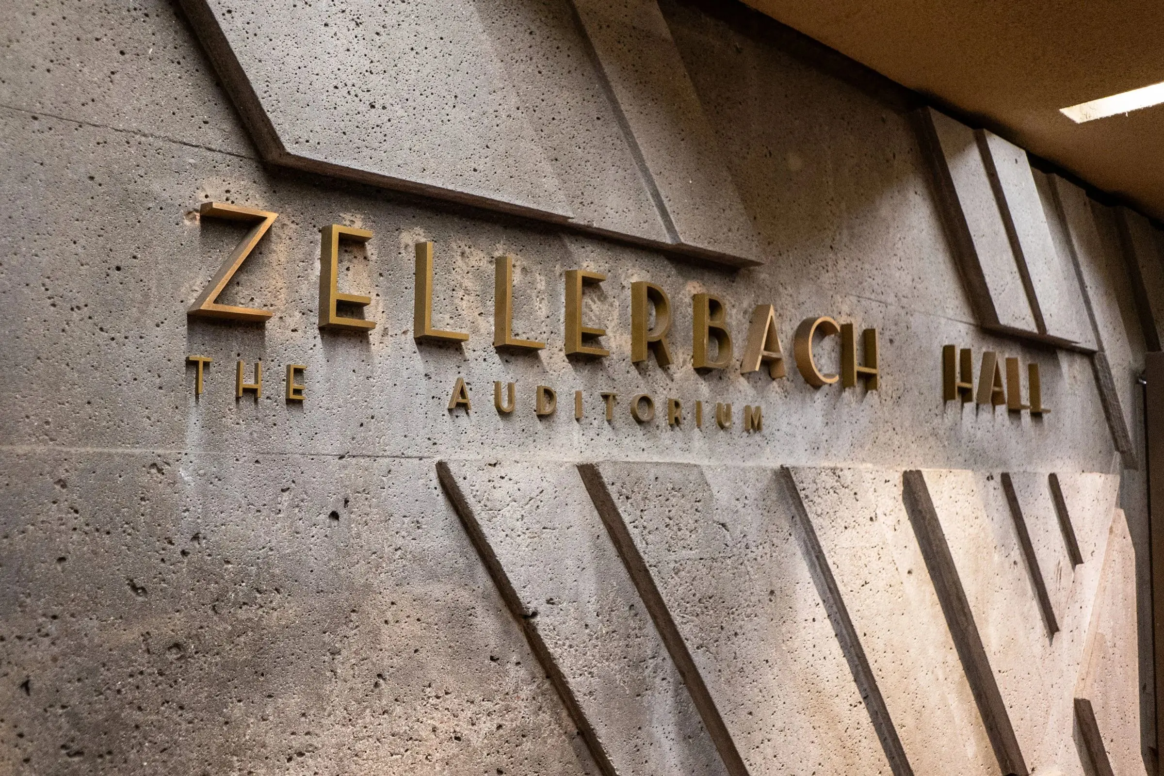 Bronze theatre lettering on a textured concrete wall